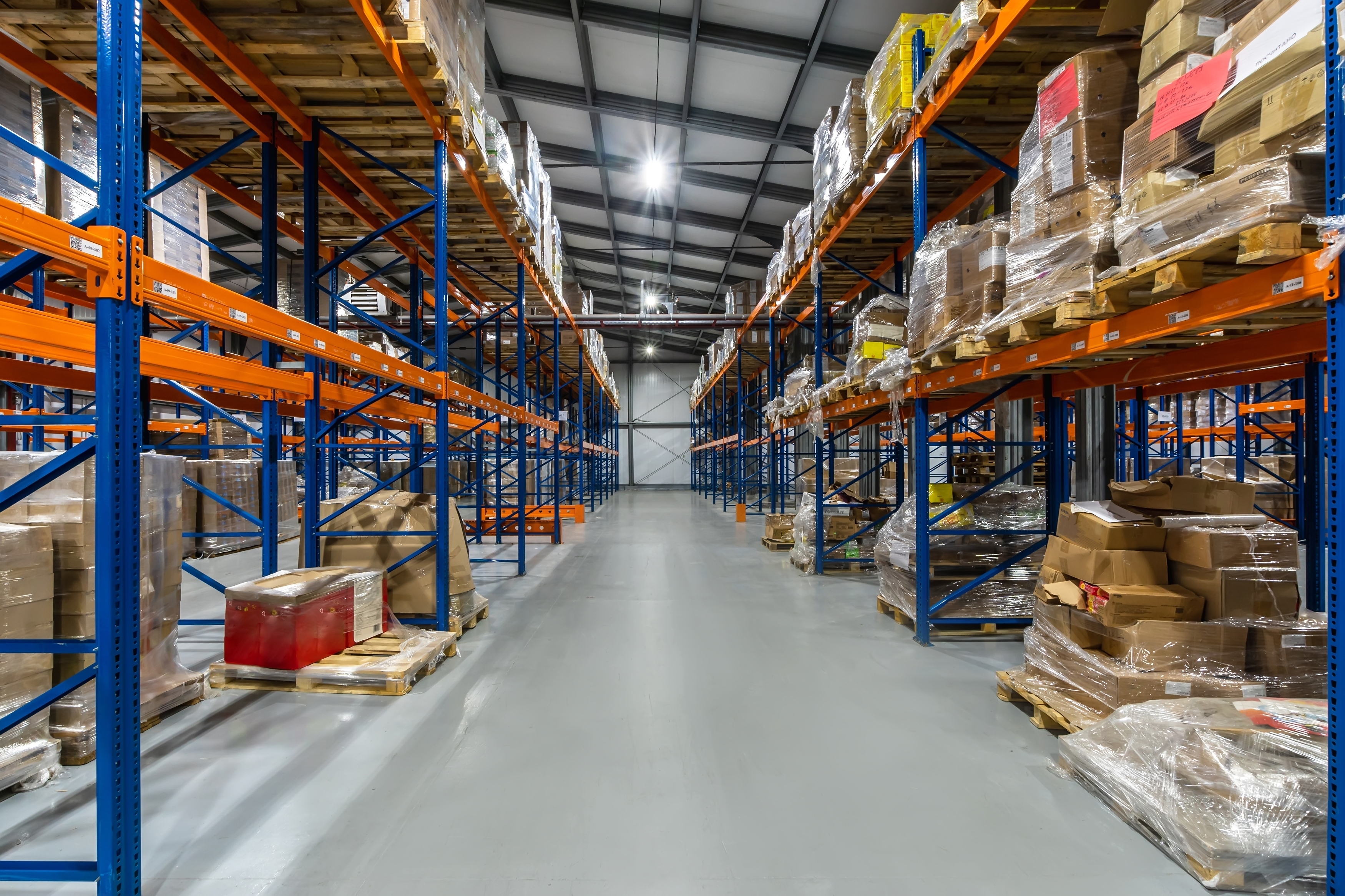 Spacious,Warehouse,Aisle,Filled,With,Stacked,Pallets,And,Boxes,In